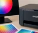 Monitor com círculo de cores e impressora Epson ao lado de charts de cor impressos